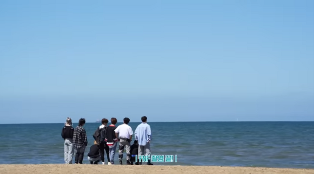 Rear view of Stray Kids standing on a beach looking at the horizon