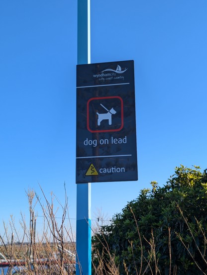 Sign on a pole saying "dog on lead. caution"