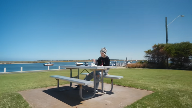 Hyunjin sitting at a picnic table with painting supplies 