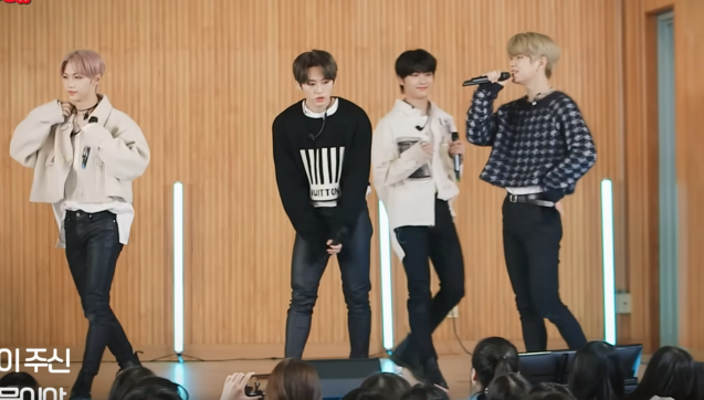 Felix, Lee Know, I.N and Seungmin performing Get Cool at a high school. Seungmin's wearing the fuzzy sweater with the tight pants and the cinched waist and he looks adorable.